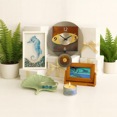 Artisan gifts featuring a seahorse mosaic, clock, sand art, bracelet on a ginkgo dish, and a candle on a white background.