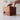 Wooden puzzle box with a hand attempting to open it on a light surface.
