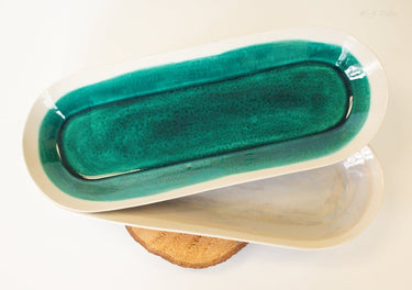 Ceramic butter dish with green interior and beige exterior on a white background