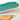 Teal ceramic tray on a white surface with a wooden coaster underneath