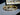 Gold bracelet on a reflective surface with a blurred background