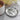 Decorative silver coaster with tree design and text on a marble surface with a cup of coffee and flowers.