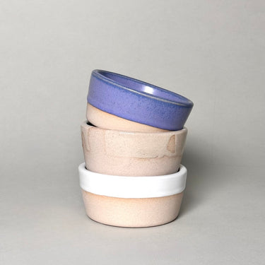 Stack of three ceramic bowls with different colored rims on a gray background