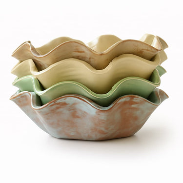 Stack of ceramic ruffled bowls in various colors on a white background