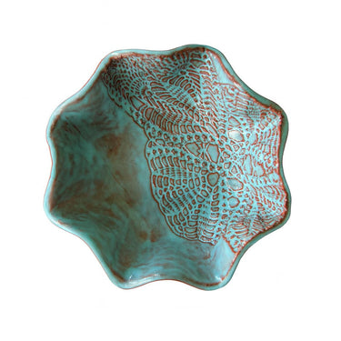 Turquoise ceramic bowl with textured design on a white background