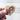 Wooden heart-shaped object with a purple ribbon design held by a hand against a light background