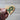 Wooden heart-shaped object with a green ribbon design held by a hand against a neutral background