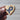 Wooden heart-shaped object with a blue ribbon symbol held by a hand against a neutral background