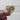 Wooden heart-shaped pin with a blue ribbon design held by a hand against a white background