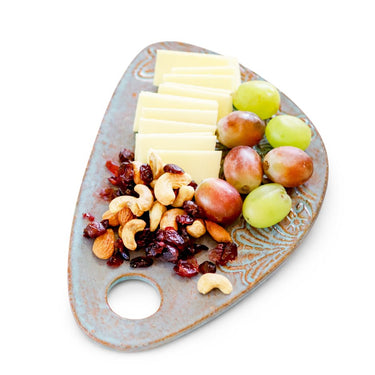 Cheese Borads with sliced cheese, grapes, nuts, and dried fruits on a decorative plate.