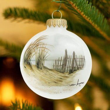 Decorative Christmas ornament with a beach scene drawing on a tree branch.