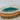 Ceramic dish with teal interior on a wooden block against a white background