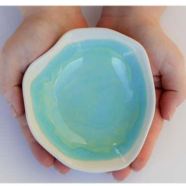 Hand holding a heart-shaped ceramic dish with a blue interior