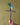Metallic dragonfly cross sculpture held by a hand against a green background