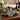 Emerald City Blossom Bowl on a wooden surface with flowers and candles in the background