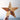 Wooden star with rustic design held against a light background