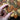 Hand holding a wooden heart with a treble clef design against a background of similar hearts.