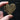 Heart-shaped wooden object with engraved text held by a hand against a dark background