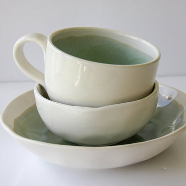 Stack of ceramic bowls on a white plate with a white background