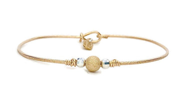 Gold bracelet with a spherical charm on a white background