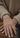 Close-up of a hand wearing a delicate bracelet on a neutral background