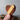 Wooden heart-shaped object held by a hand against a neutral background