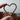 Hand holding a copper heart-shaped object with blurred background