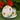 Candle in a tin with floral design and visible brand name on a green surface with red flowers in the background