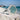 Silver ring with a light blue gemstone on a sandy beach