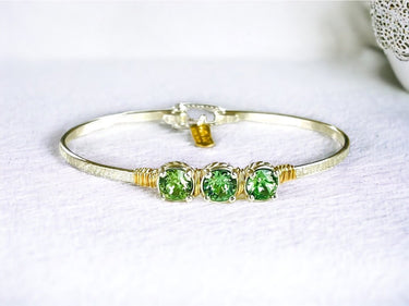 Gold bracelet with green gemstones on a white background
