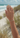 Hand wearing a silver bracelet on a beach with ocean and sky in the background