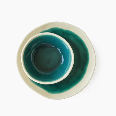 Teal ceramic bowl with white rim on a white background