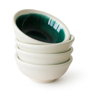 Stack of white ceramic bowls with green interior on a white background