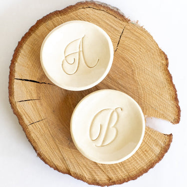 Two round soap bars with monogram designs on a wooden surface