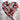 Heart-shaped mosaic art piece held by a hand against a light background