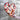 Heart-shaped mosaic art piece held by a hand against a textured wall background