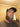 Man with a beard wearing a cap indoors against a beige wall.