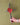 Hand holding a metal cross with a red heart against a green wall