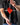Person holding a red heart-shaped object with metal tongs against a dark background