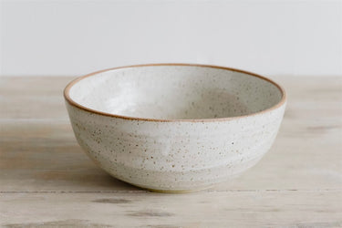 White ceramic bowl with brown rim on a wooden surface