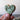 Heart-shaped wooden stamp with decorative design held by a hand against a neutral background