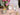 Rose of Sharon Soy Lotion Candle with floral packaging on a table with flowers and candles in the background