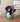 Teal vase with purple flowers on a wooden surface