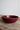 Red ceramic bowl on a wooden surface with a plain background