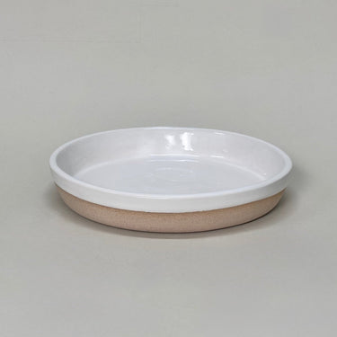 Ceramic dish with white rim and beige base on a gray background