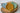 Three ceramic leaf-shaped plates in blue, green, and gold on a wooden stump.