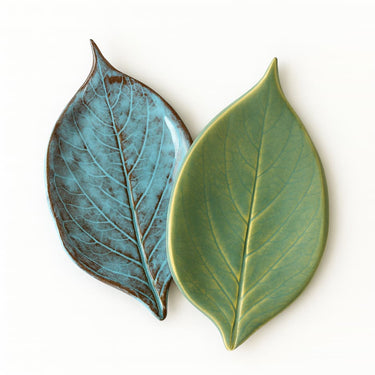 Two ceramic leaf-shaped dishes in teal and green on a white background