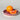 Orange and a slice of grapefruit on a pink ceramic plate against a gray background