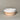 Ceramic bowl with white top and beige bottom on a neutral background