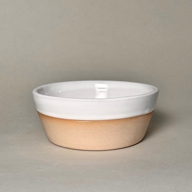 Ceramic bowl with white top and beige bottom on a neutral background